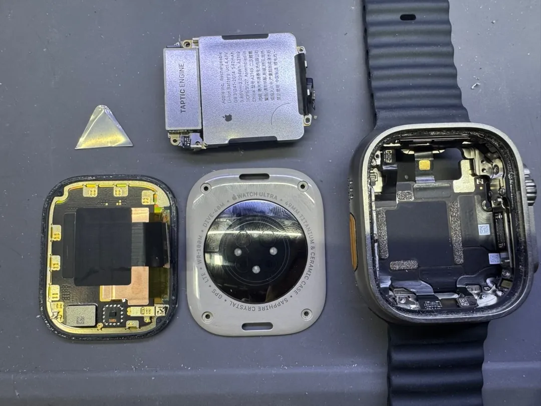 Apple Watch Ultra taken apart on an anti-static mat: display, back cover, battery and the opened case