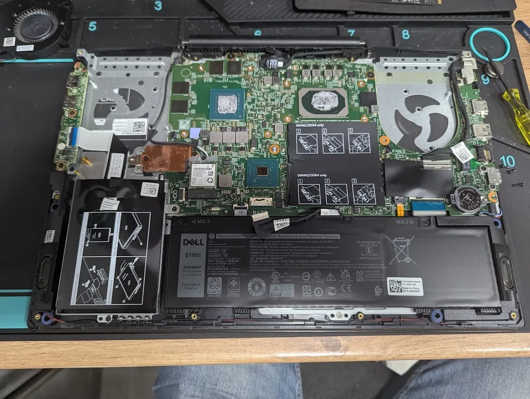 Opened Dell laptop on an anti-static mat: motherboard, cooling fans and battery