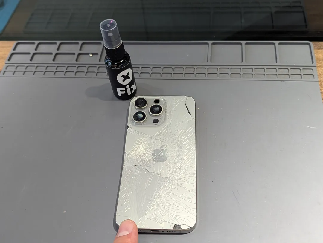 iPhone Pro with a shattered back, next to an XFix spray