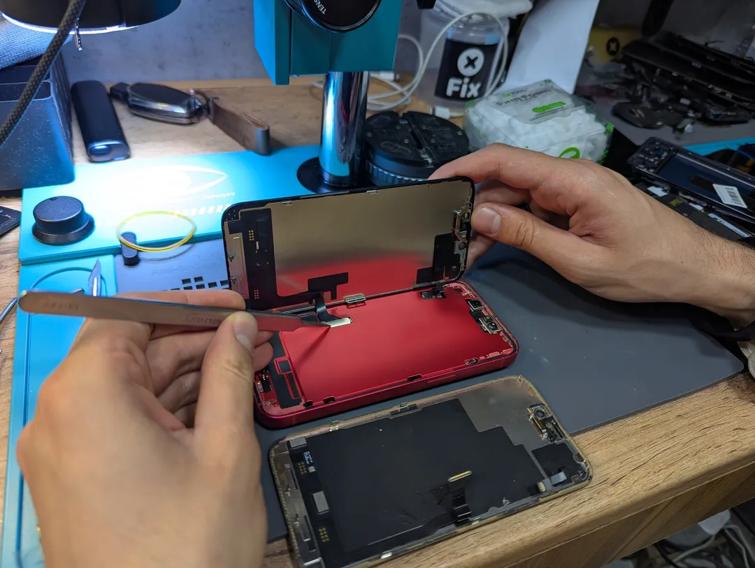Connecting a screen to an opened red iPhone at the workbench