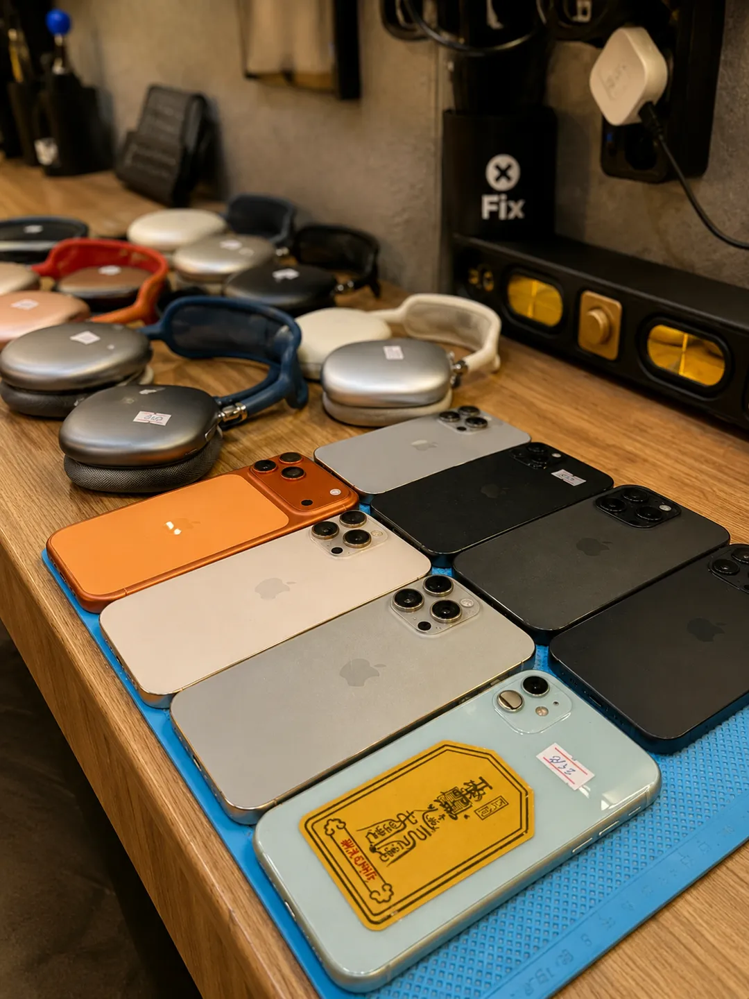 iPhones and AirPods Max headphones lined up on a workbench