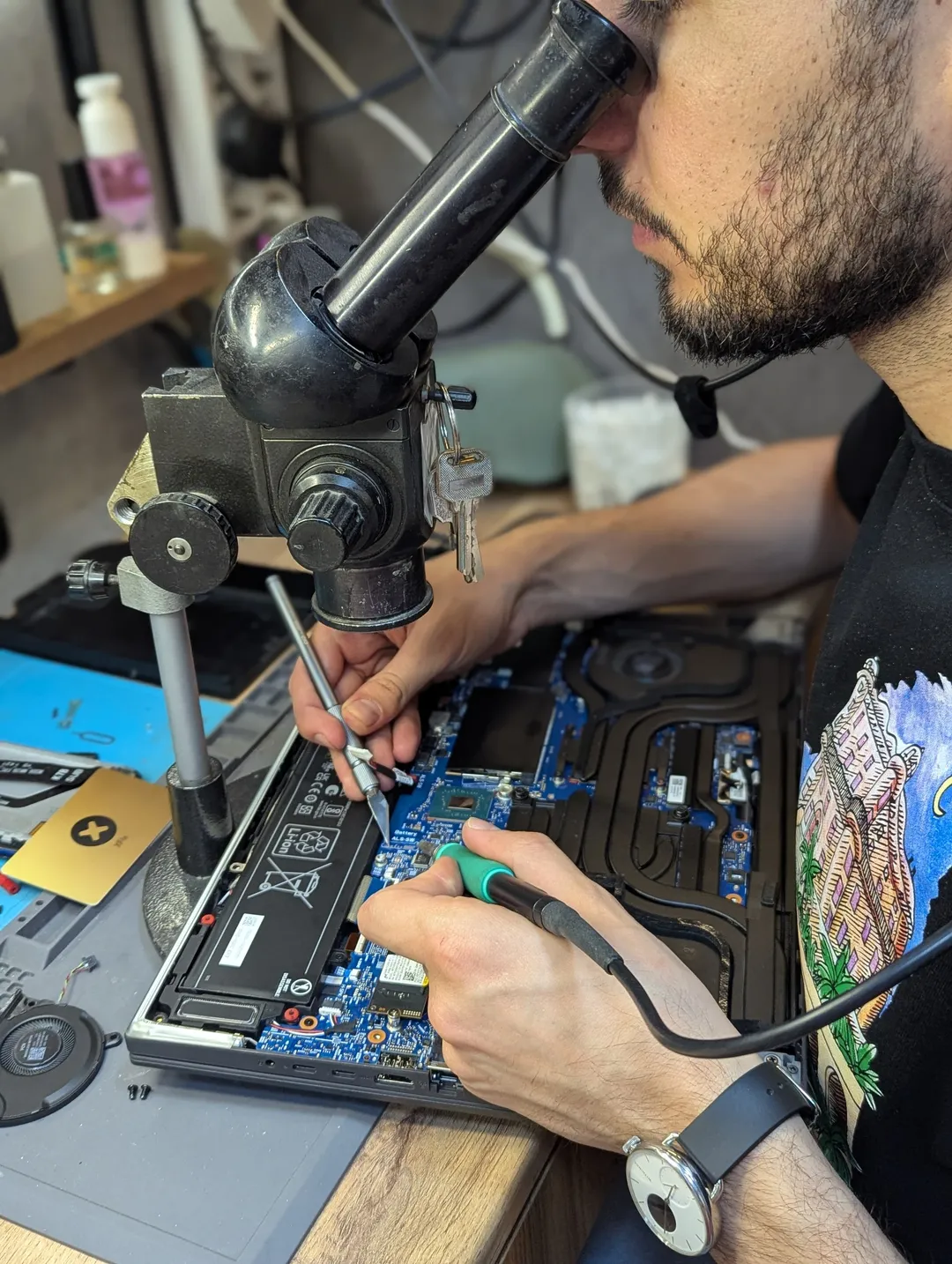 Technician soldering a laptop motherboard under the microscope