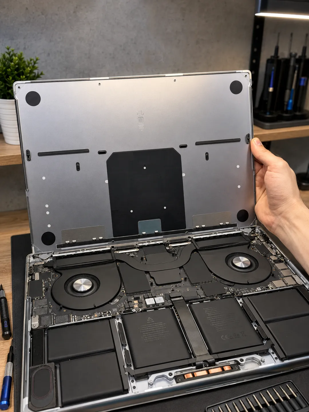 MacBook Pro with the bottom case lifted, showing the fans and batteries