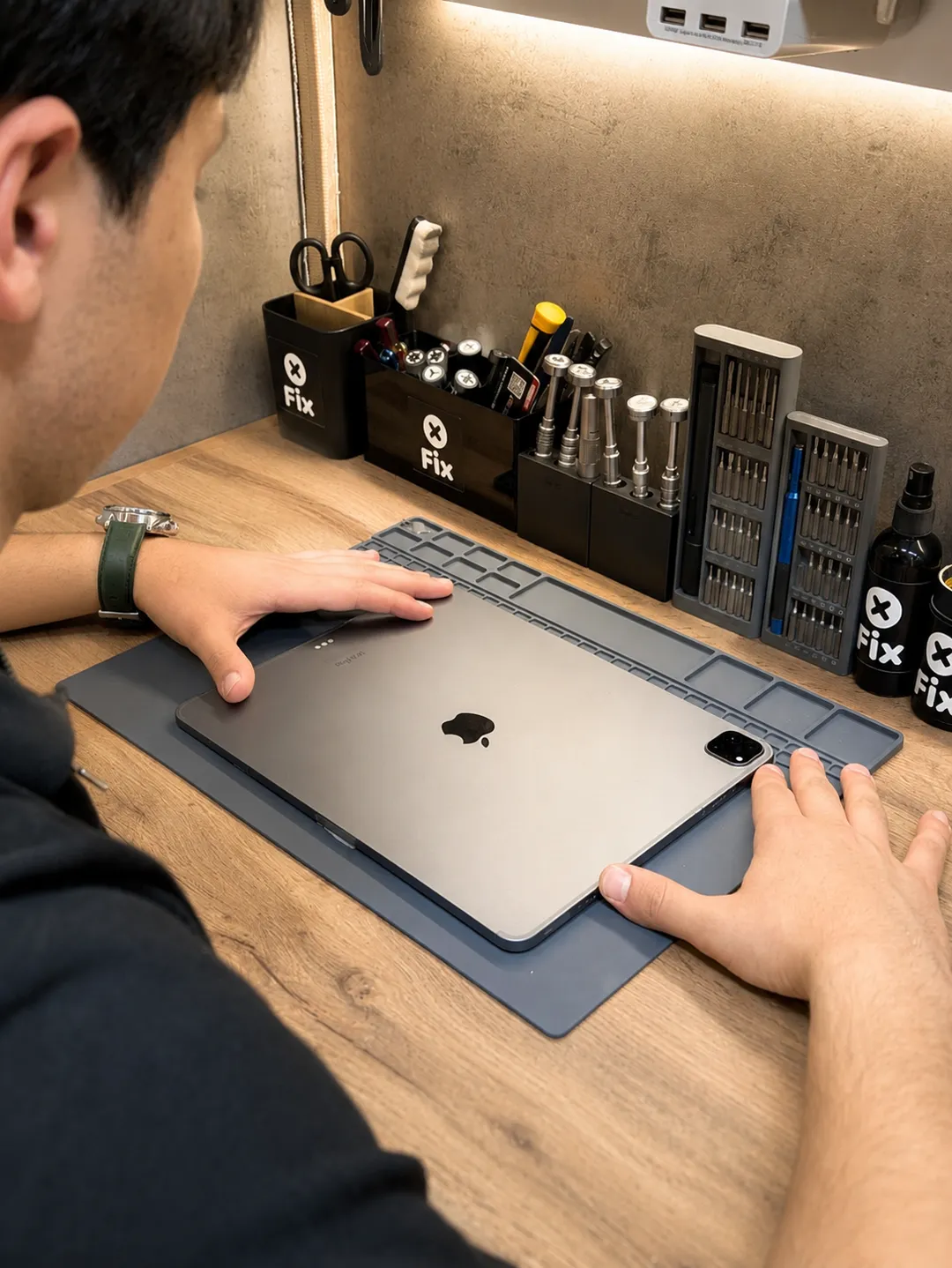 Technician at a repair bench with an iPad Pro on an anti-static mat